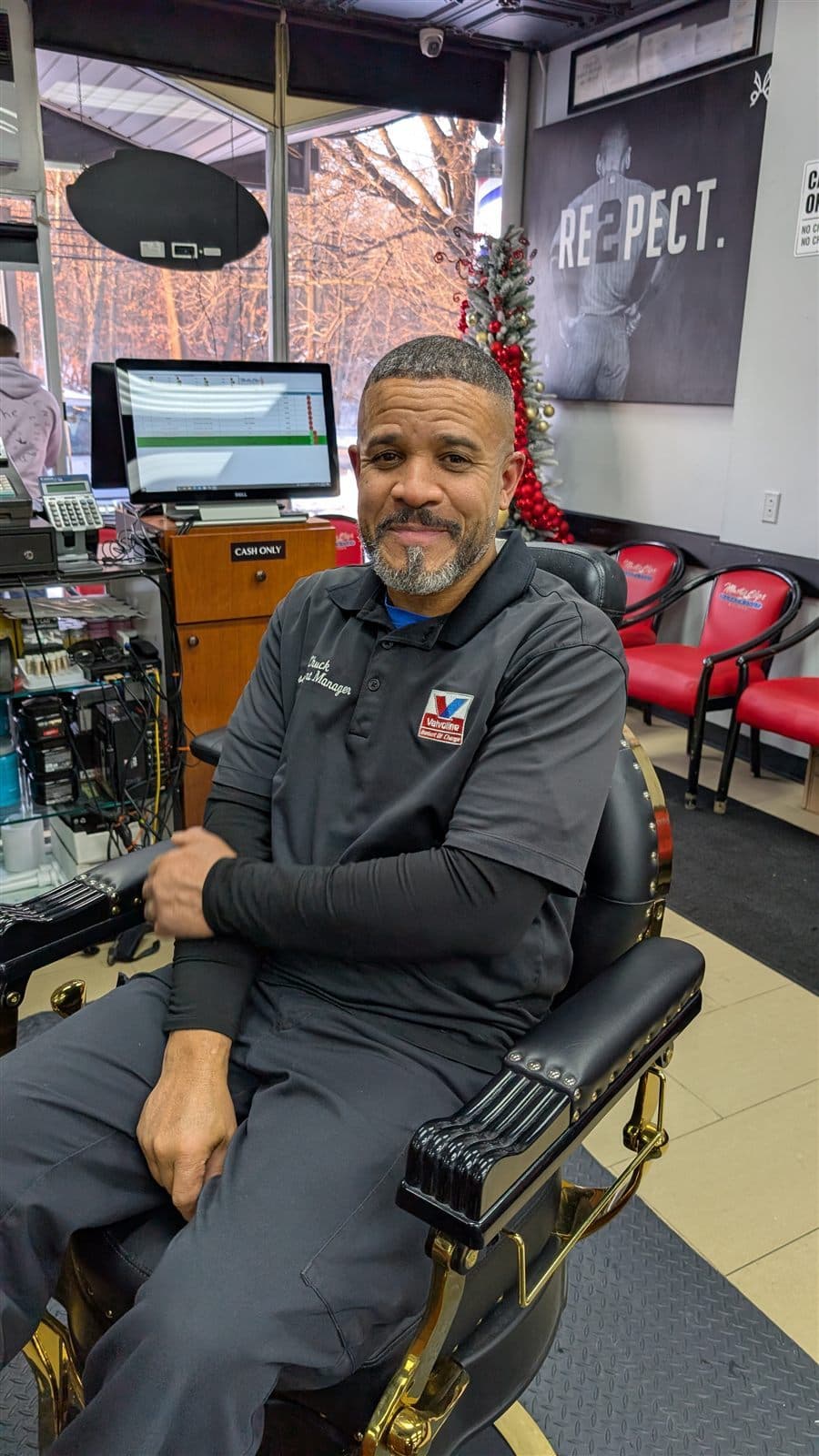 Barber seated in a Master Clips barber chair inside the Edison shop