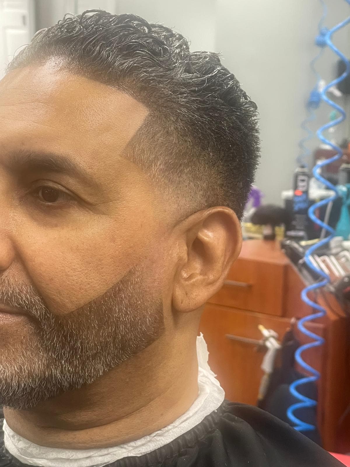 Curly textured top, low fade and precisely shaped beard