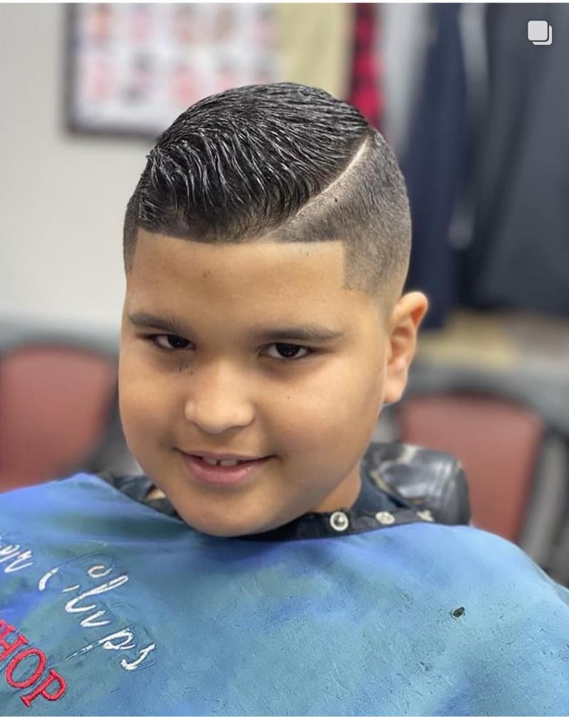 Young client with a side-part haircut, sharp line-up and low fade at Master Clips