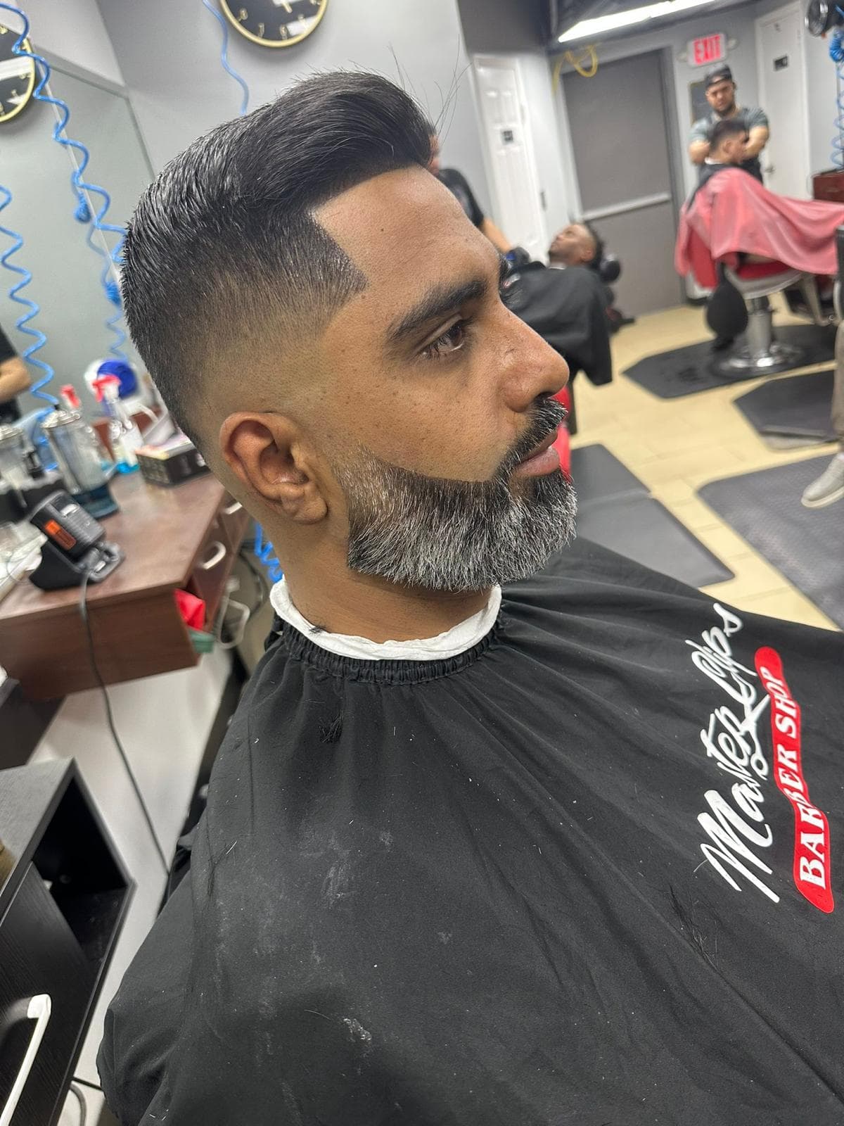 Sharp side fade with a defined hairline and detailed salt-and-pepper beard